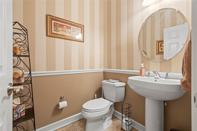 half bath featuring baseboards, tile patterned flooring, toilet, and wallpapered walls