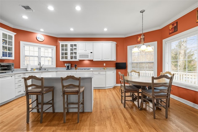 kitchen featuring white appliances, visible vents, ornamental molding, light countertops, and a healthy amount of sunlight