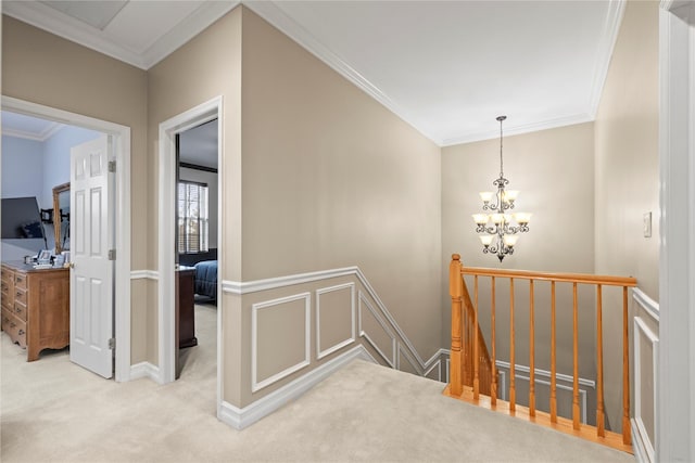 hallway with a chandelier, carpet flooring, crown molding, and an upstairs landing