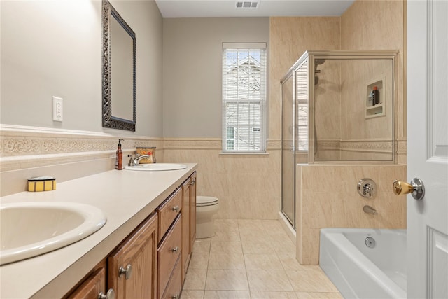 full bathroom with a wainscoted wall, a shower stall, a sink, and tile patterned floors