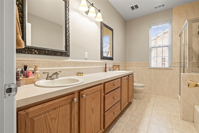 bathroom featuring a stall shower, a wainscoted wall, visible vents, and a sink