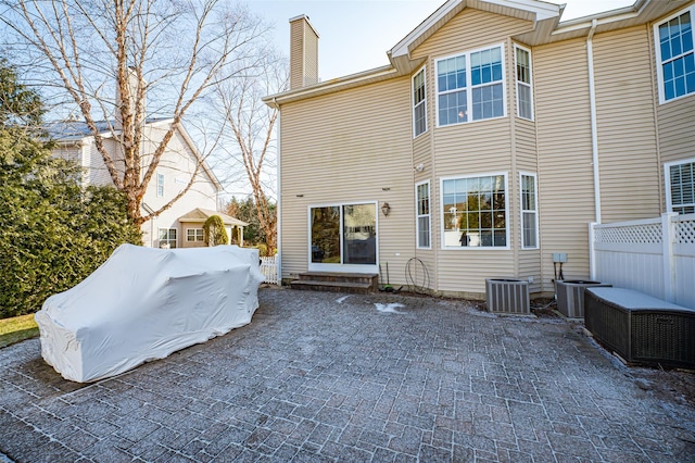 rear view of property with entry steps, a chimney, a patio area, and fence