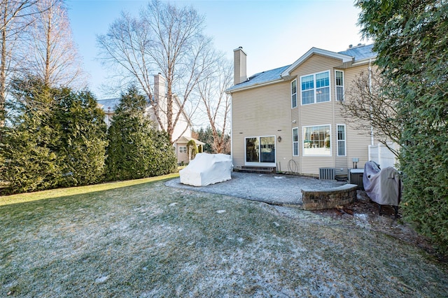 back of property featuring a patio, a chimney, and a lawn