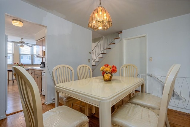 dining area featuring light wood-style flooring, stairway, and ceiling fan with notable chandelier