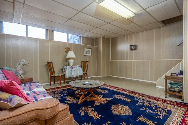 living room with wood walls, stairs, and a drop ceiling