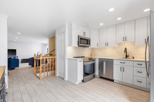 kitchen featuring a sink, stainless steel appliances, white cabinets, and light countertops