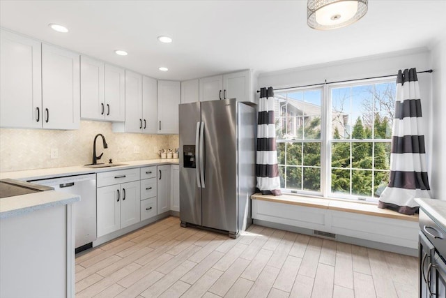 kitchen with light countertops, dishwashing machine, decorative backsplash, stainless steel fridge, and a sink