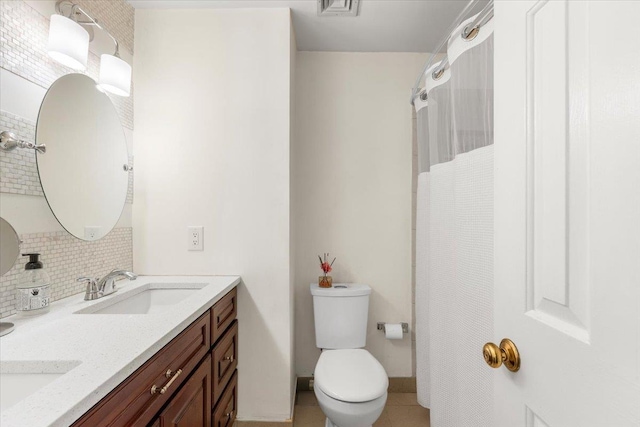 bathroom with toilet, a shower with curtain, a sink, double vanity, and decorative backsplash