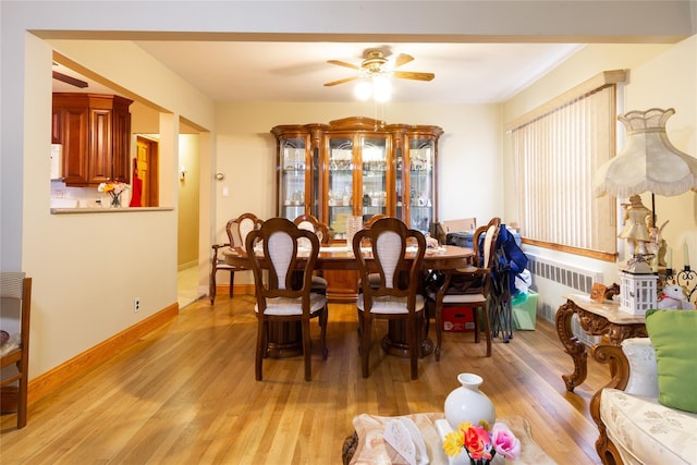 dining room featuring baseboards, ceiling fan, light wood finished floors, and radiator