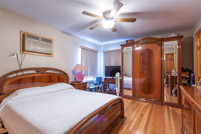 bedroom with a ceiling fan, a wall mounted air conditioner, and light wood finished floors