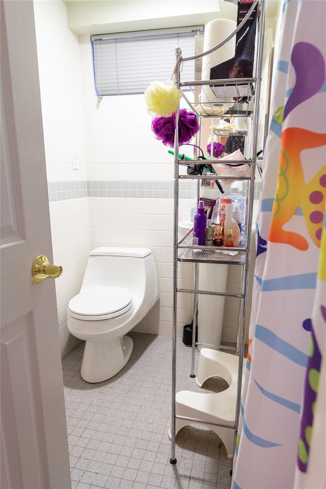 bathroom with tile patterned flooring, a shower with shower curtain, tile walls, and toilet