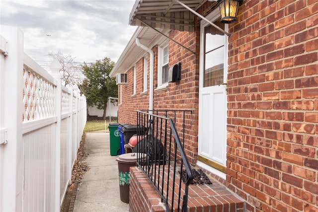 view of property exterior with brick siding and fence