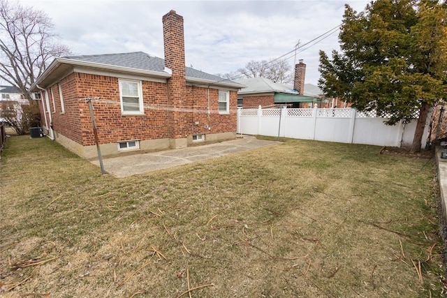 rear view of house with a chimney, fence, a lawn, and brick siding