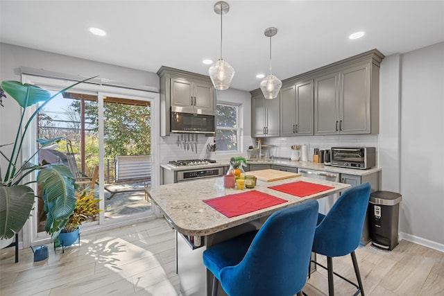 kitchen with decorative backsplash, appliances with stainless steel finishes, light wood-style floors, and gray cabinetry