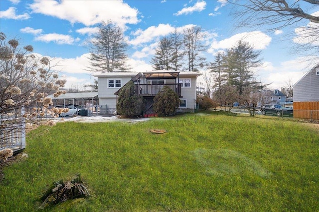 rear view of property featuring a yard, a carport, a deck, and fence