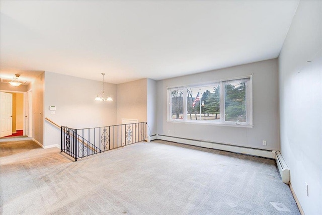 carpeted empty room with a baseboard heating unit, baseboards, and a chandelier