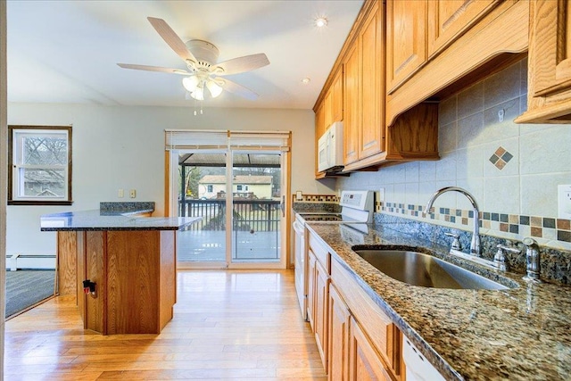 kitchen with light wood finished floors, a healthy amount of sunlight, white appliances, and a sink