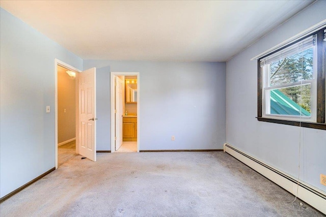 unfurnished bedroom with light colored carpet, connected bathroom, a baseboard heating unit, and baseboards