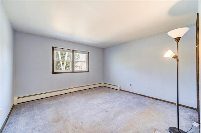 empty room featuring carpet flooring, a baseboard heating unit, and baseboards