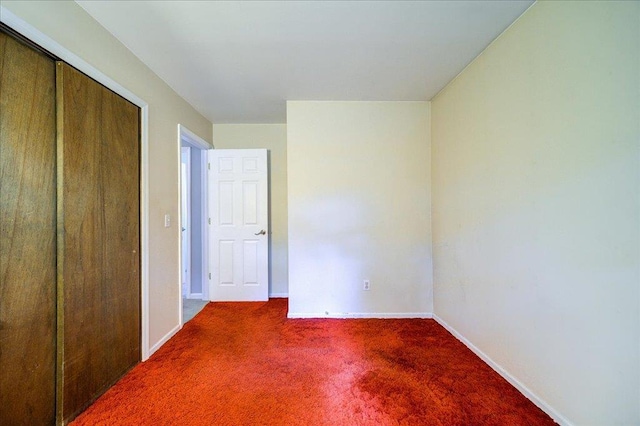 unfurnished bedroom with carpet flooring, baseboards, and a closet