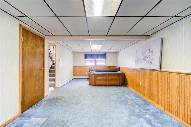 bar featuring wood walls, carpet flooring, a paneled ceiling, baseboard heating, and stairs