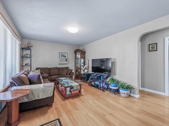 living room featuring baseboards, arched walkways, and wood finished floors