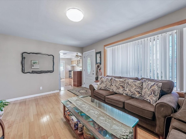 living area featuring light wood-style flooring, baseboards, and ceiling fan