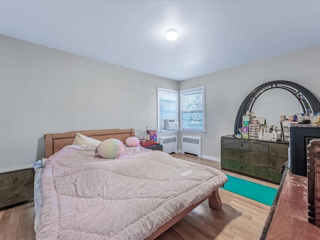 bedroom featuring baseboards, wood finished floors, and radiator