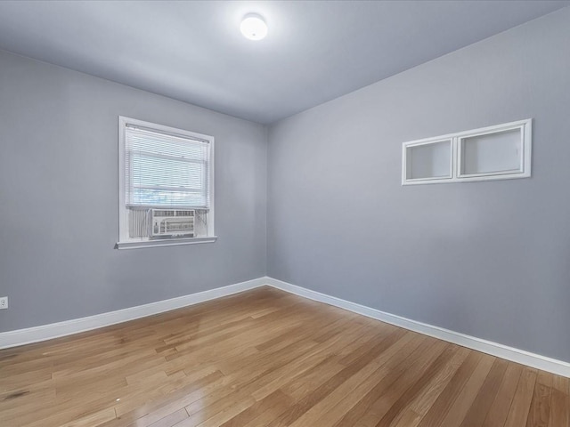 empty room featuring light wood-style flooring, baseboards, and cooling unit