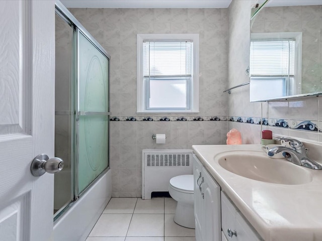 bathroom with radiator, toilet, enclosed tub / shower combo, vanity, and tile patterned floors