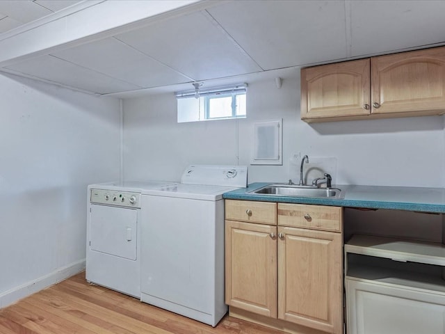 laundry area featuring a sink, baseboards, light wood-type flooring, cabinet space, and washing machine and clothes dryer