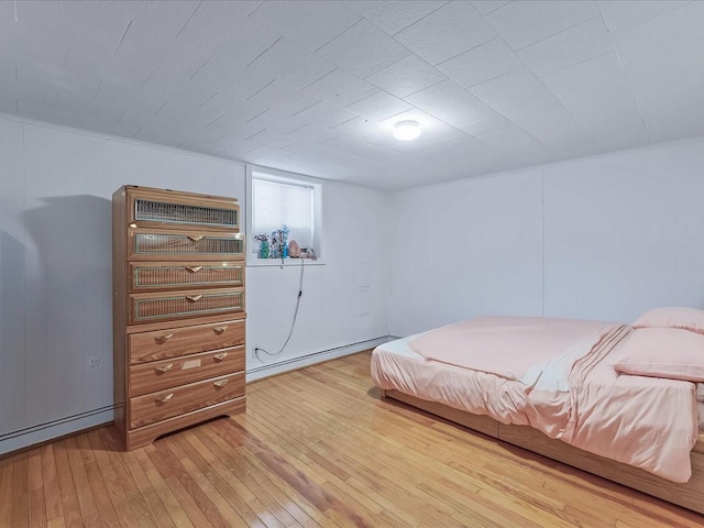 bedroom with a baseboard heating unit and light wood finished floors