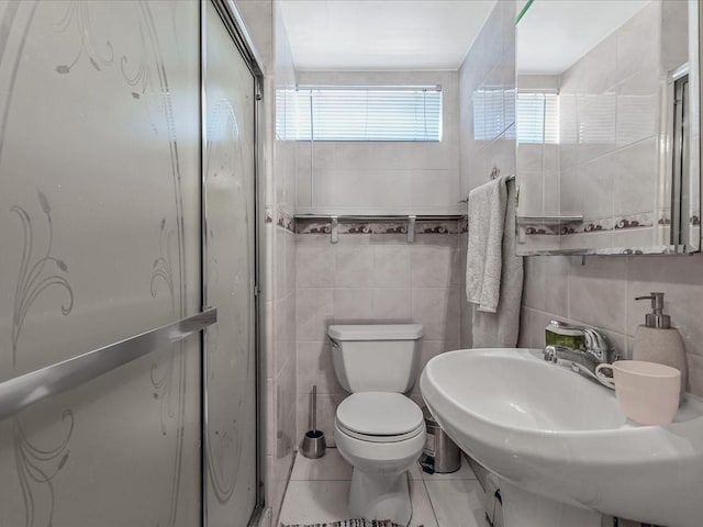 full bathroom with toilet, a sink, tile patterned flooring, an enclosed shower, and tile walls