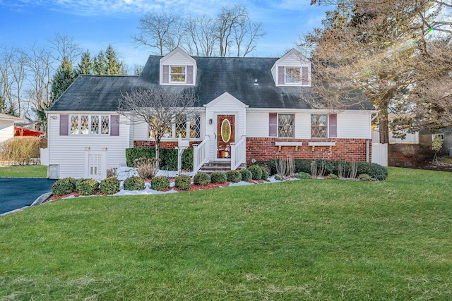 cape cod home with brick siding, aphalt driveway, and a front yard