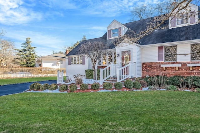 view of front of property featuring aphalt driveway, a front lawn, and brick siding