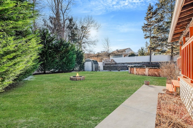 view of yard featuring a storage shed, a fenced backyard, an outdoor fire pit, and an outbuilding