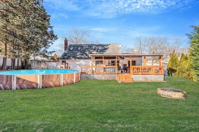 rear view of property with a fire pit, a yard, a chimney, and a wooden deck