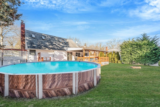 outdoor pool with a deck and a lawn