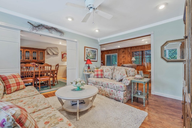 living area featuring baseboards, wood finished floors, and crown molding