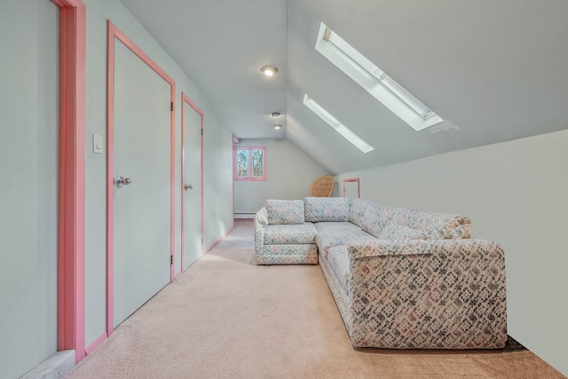 carpeted living area featuring vaulted ceiling with skylight and baseboard heating