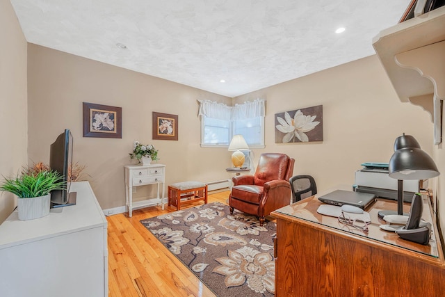 office area featuring light wood-style flooring, baseboards, baseboard heating, and a textured ceiling