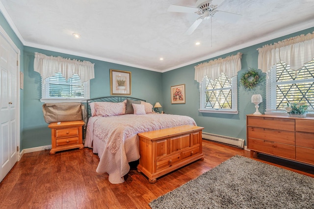 bedroom featuring crown molding, a baseboard heating unit, a ceiling fan, wood finished floors, and baseboards