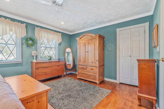 bedroom featuring ornamental molding, light wood-type flooring, a ceiling fan, and baseboards