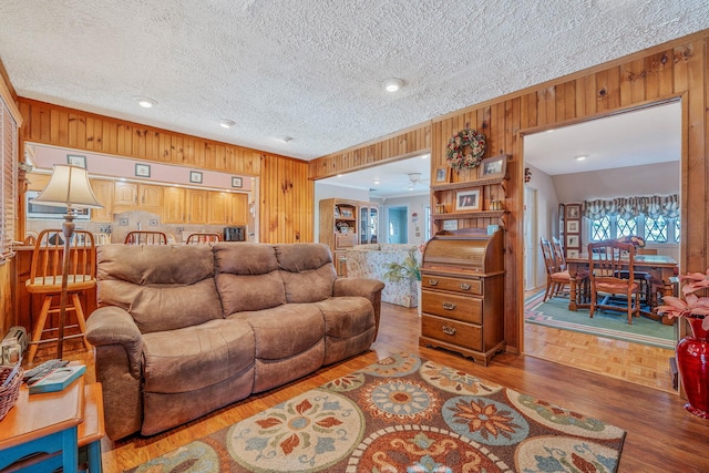 living area with wood walls, a textured ceiling, and parquet flooring