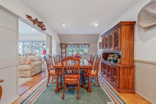 dining area featuring vaulted ceiling, baseboards, and parquet flooring