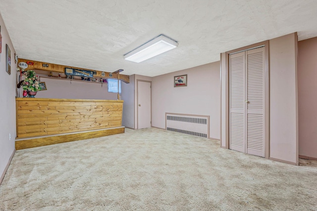 interior space featuring radiator, carpet flooring, and a textured ceiling