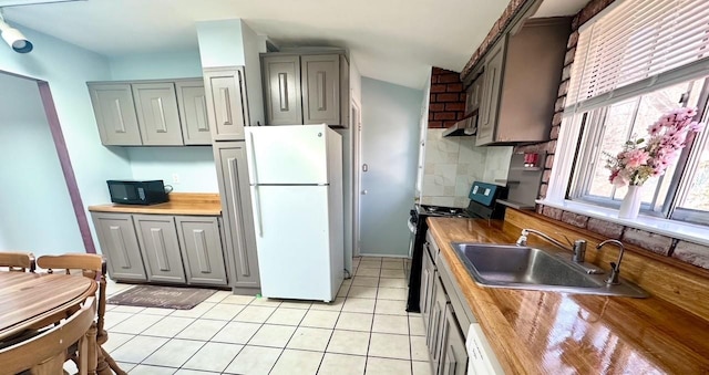 kitchen featuring under cabinet range hood, a sink, backsplash, gray cabinets, and black appliances