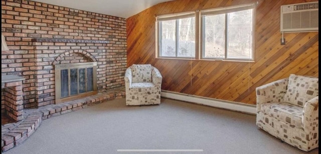 unfurnished room with wooden walls, carpet floors, baseboard heating, a brick fireplace, and a wall mounted air conditioner