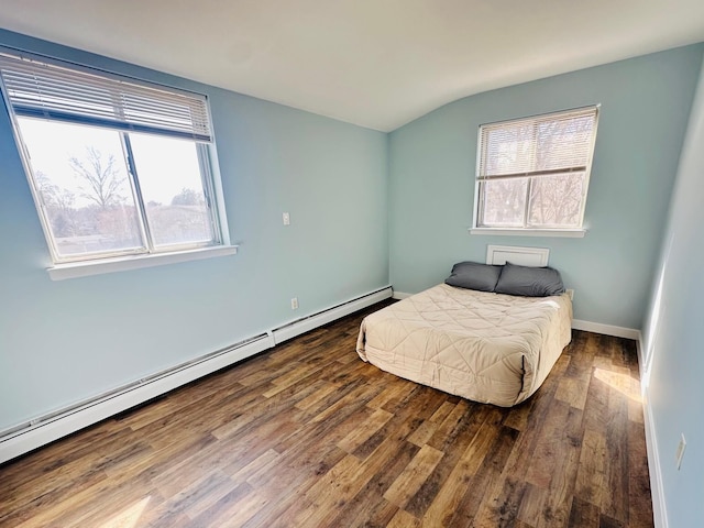 bedroom with a baseboard heating unit, vaulted ceiling, wood finished floors, and baseboards