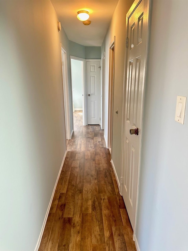 corridor featuring dark wood-style floors and baseboards